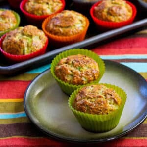 square image of Flourless Savory Breakfast Muffins with two muffins on plate and baking sheet of muffins in background
