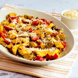 Val's Easy Yellow Squash with Tomatoes and Parmesan shown on serving plate with Parmesan in back.