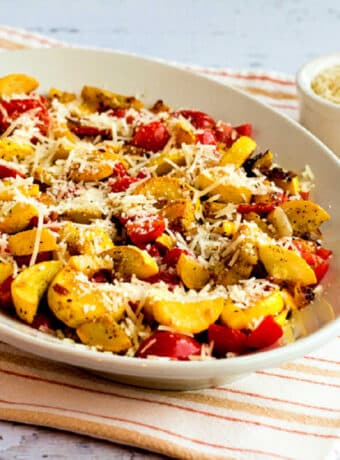 Val's Easy Yellow Squash with Tomatoes and Parmesan shown on serving plate with Parmesan in back.