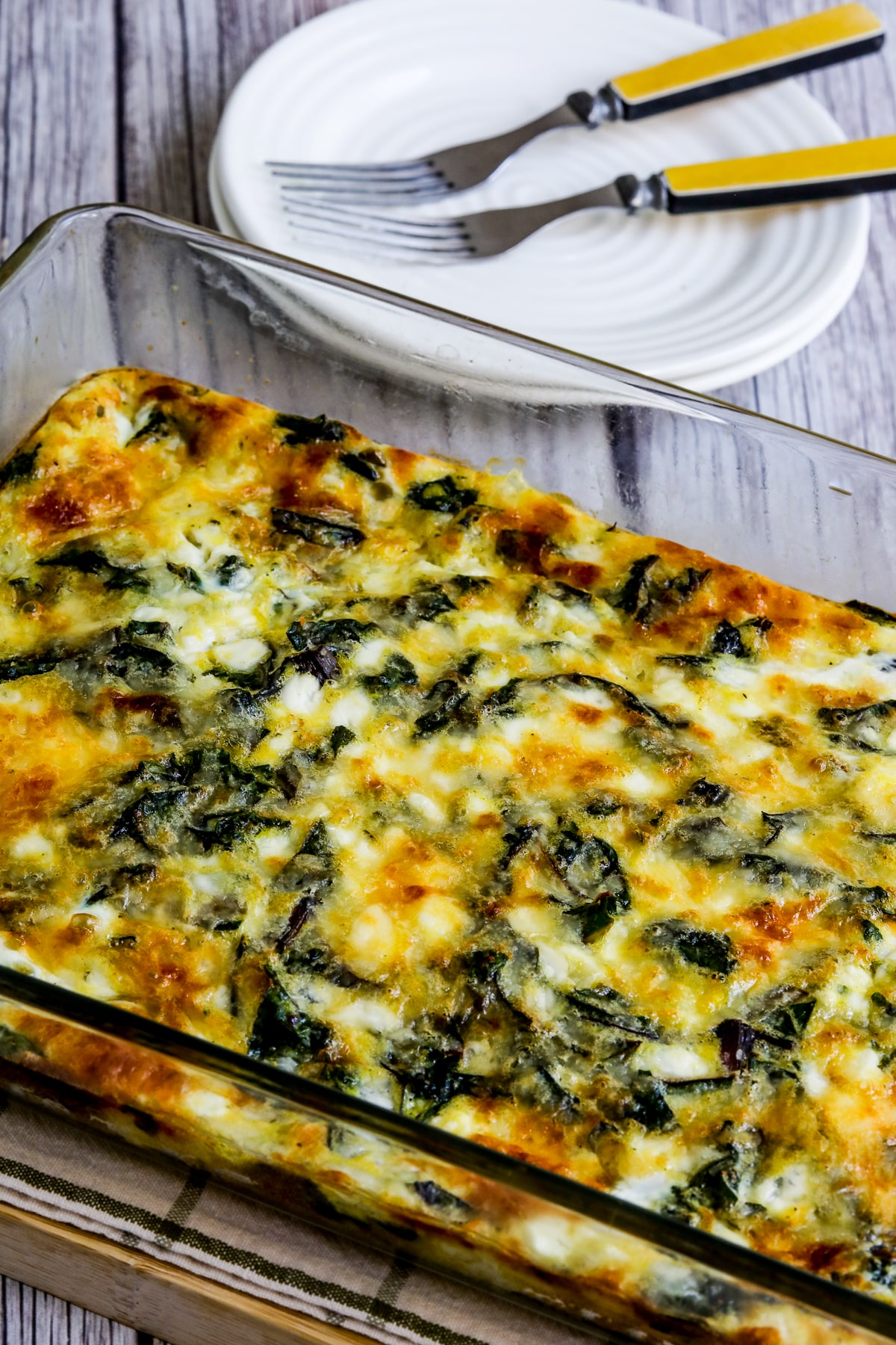 Swiss Chard Egg Bake (with Cottage Cheese) Shown in baking dish with plates in back.