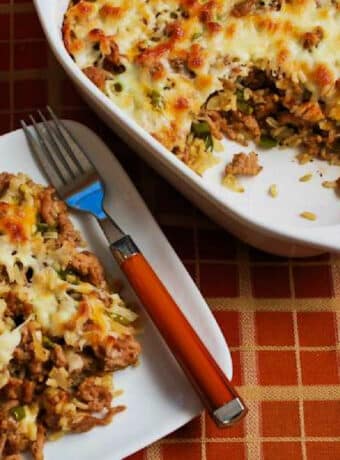 Square image for Brown Rice Casserole with Sausage and Peppers shown with one serving on plate and baking dish in back.