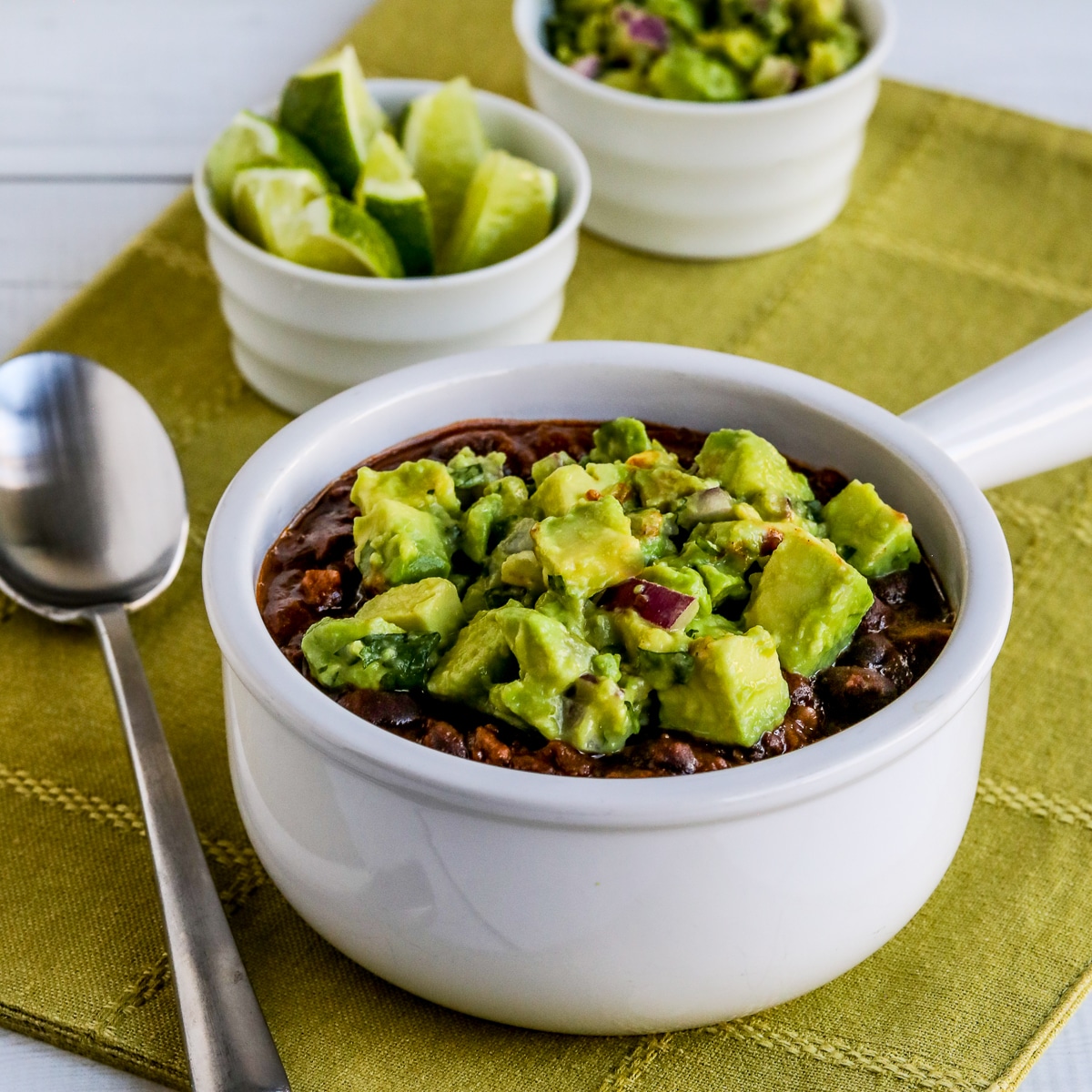 Square image for Black Bean and Beef Chili, shown in bowl with limes and salsa.