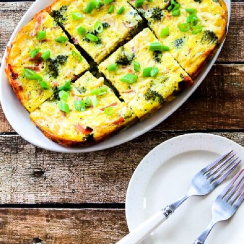 Slow Cooker Breakfast Casserole with Broccoli, Ham, and Swiss shown on serving platter with plates and forks.