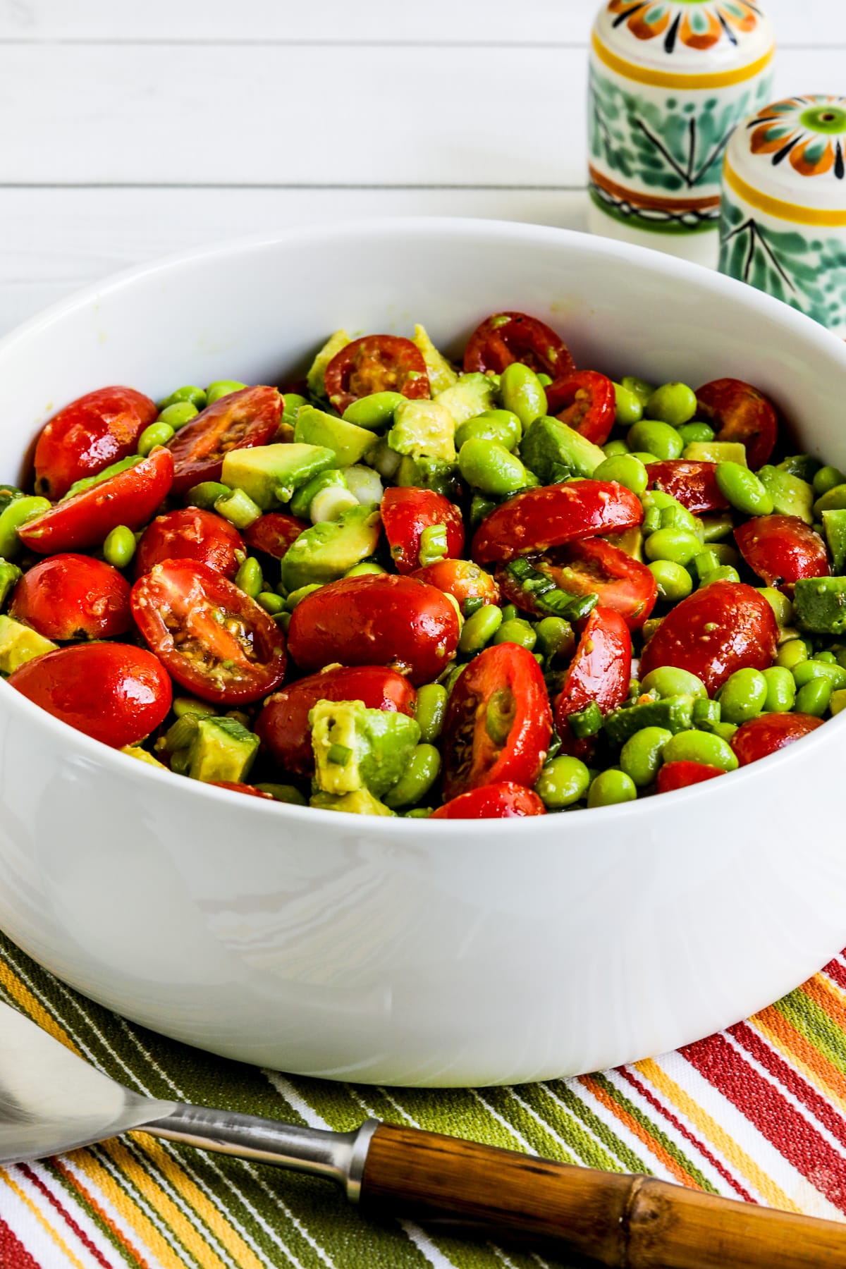 Tomato Avocado Salad with Edamame shown in large serving bowl with serving fork.