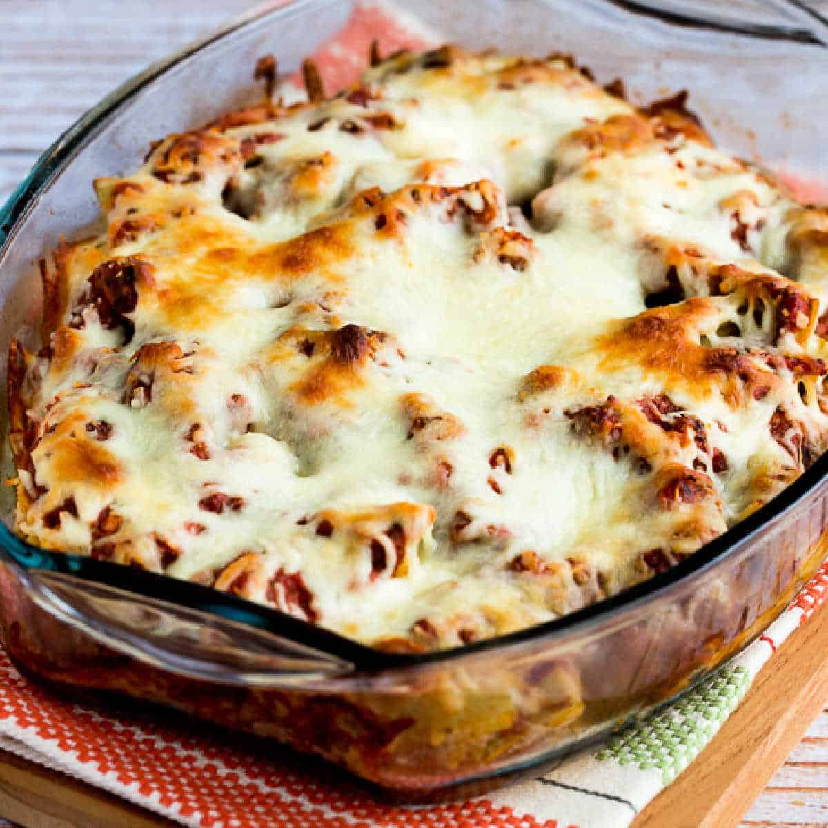 Square image of Meatball Casserole with Artichokes shown in baking dish with melted cheese.