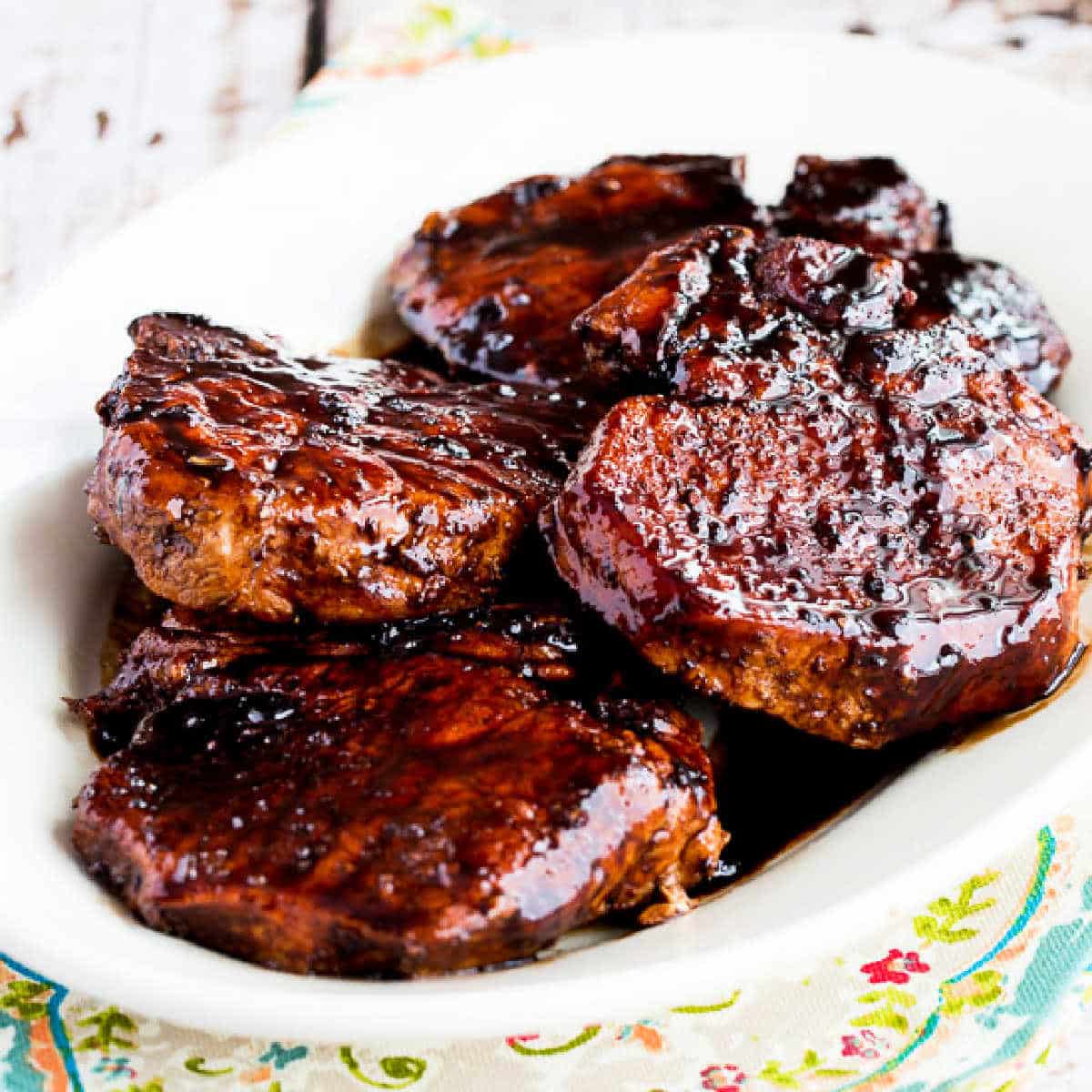 Square image of pork chops with balsamic glaze shown on a serving platter.