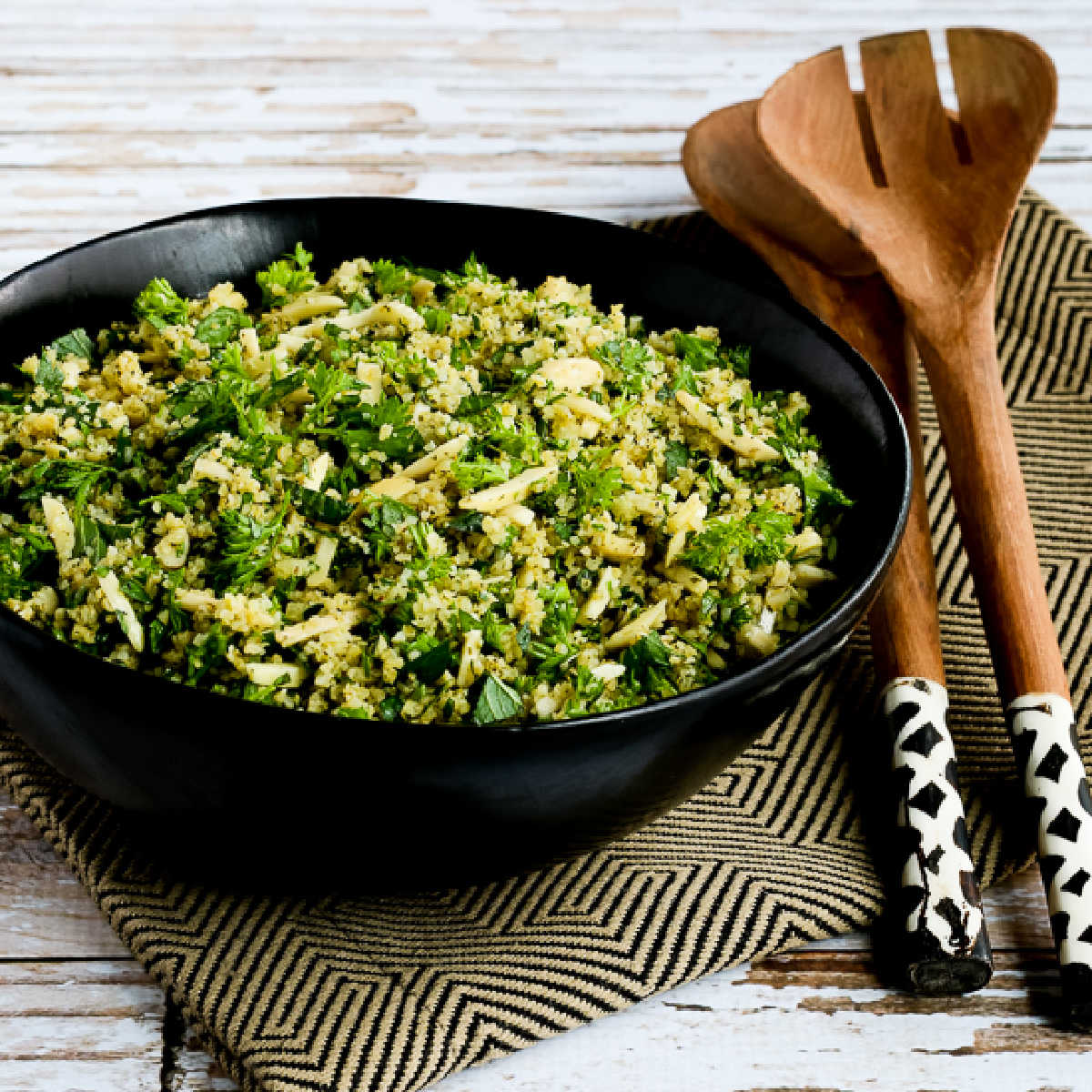 Tabbouleh Salad with Almonds in black bowl with decorative salad forks.