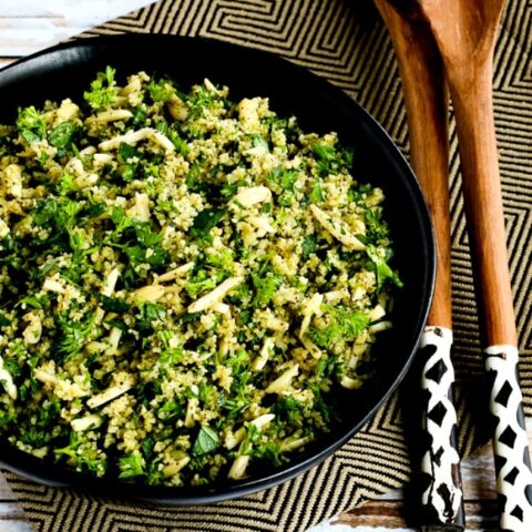 Tabbouleh with Almonds shown in serving bowl with decorative napkin and serving spoons