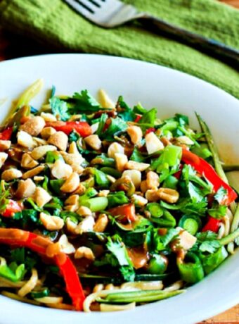 Zucchini Noodle Bowl with Peanut Sauce on wood table with green napkin