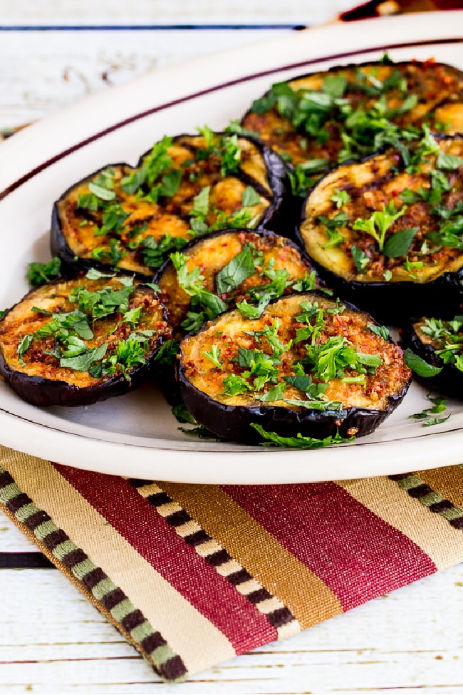 Spicy Grilled Eggplant shown on serving plate with herbs