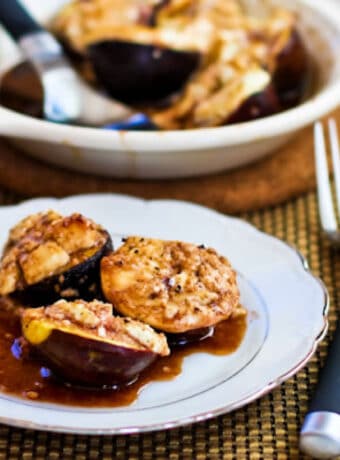 Roasted Figs with Goat Cheese shown with some on serving plate and baking dish in back.
