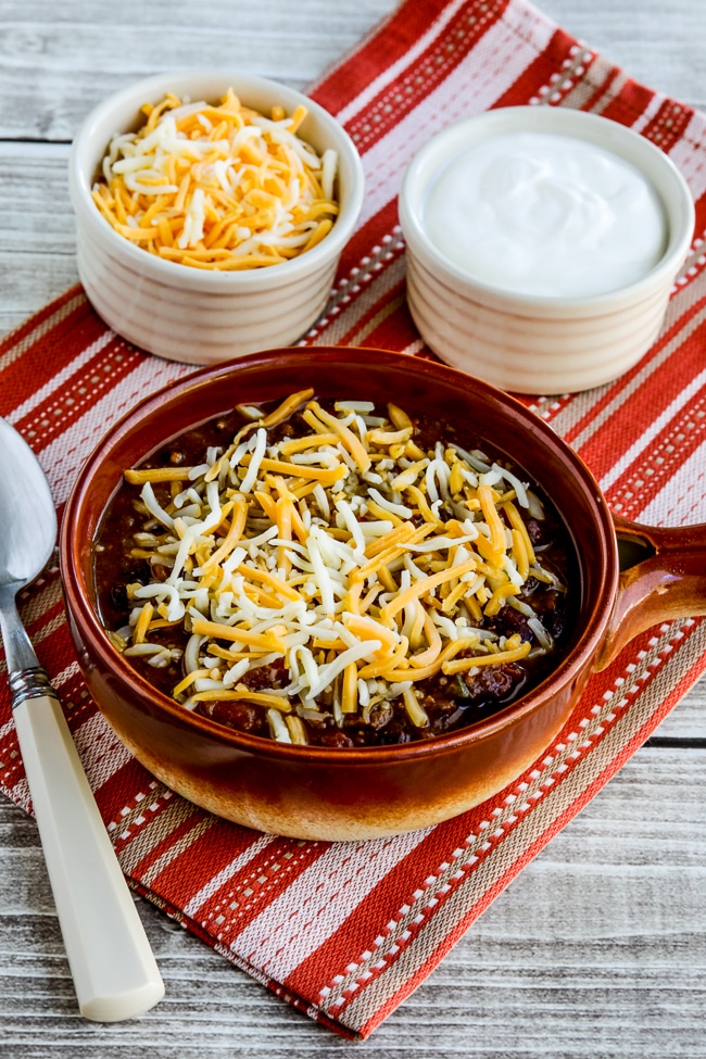 Pumpkin chili with minced meat in a bowl with the side toppings