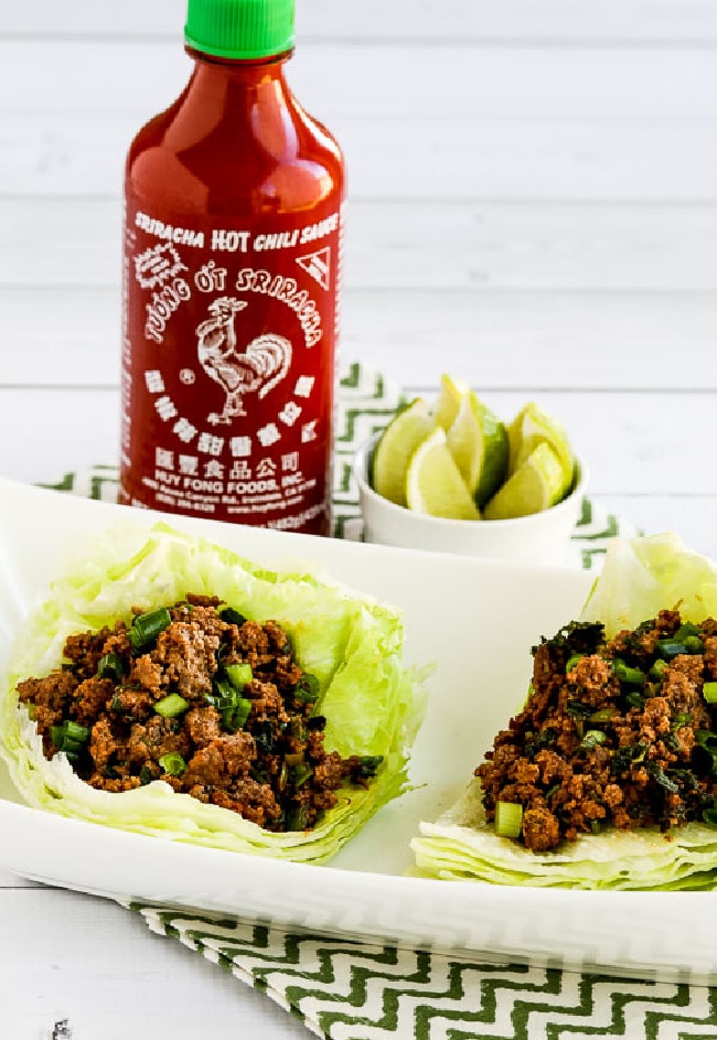Sriracha Beef Lettuce Wraps two lettuce wraps with Sriracha in background