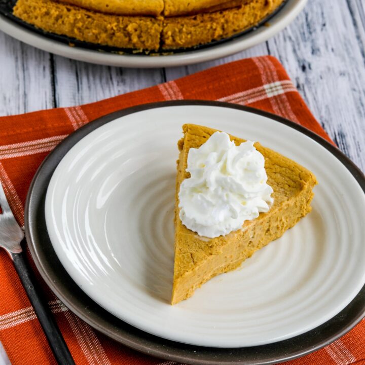 Sugar-Free Pumpkin Cheesecake Pie shown on serving plate with rest of pie on plate in background