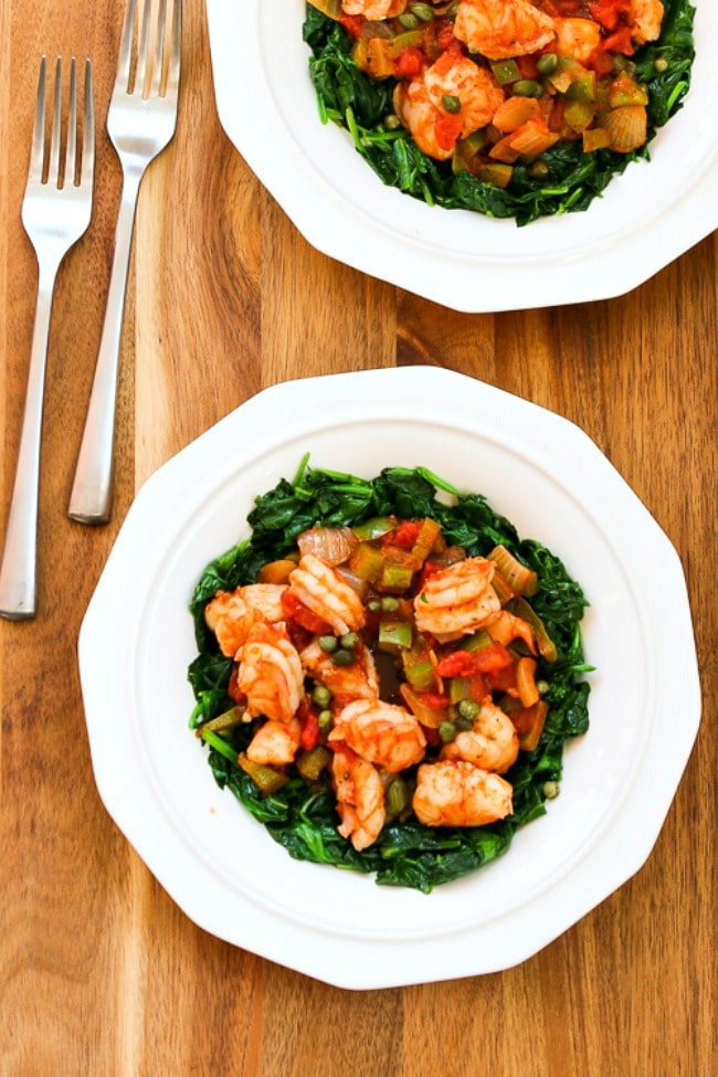 Mediterranean Shrimp over Spinach in two serving bowls with forks