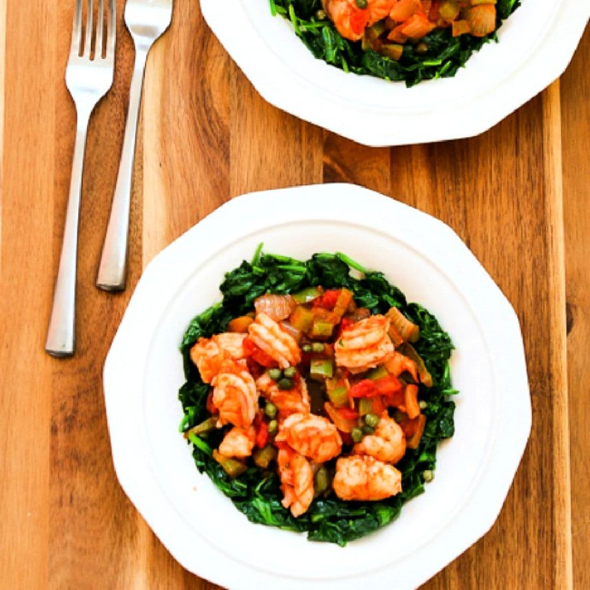 Mediterranean Shrimp with Spinach shown on serving plates with forks.