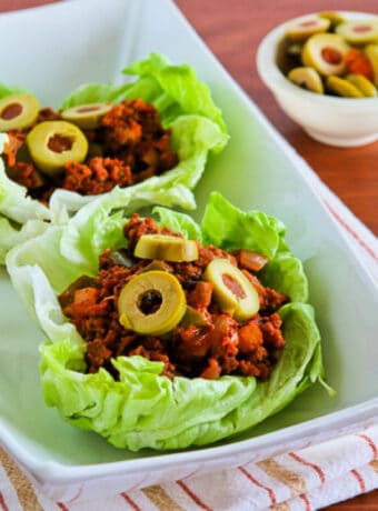 Square image of Turkey Picadillo shown in lettuce wraps with green olive garnish.