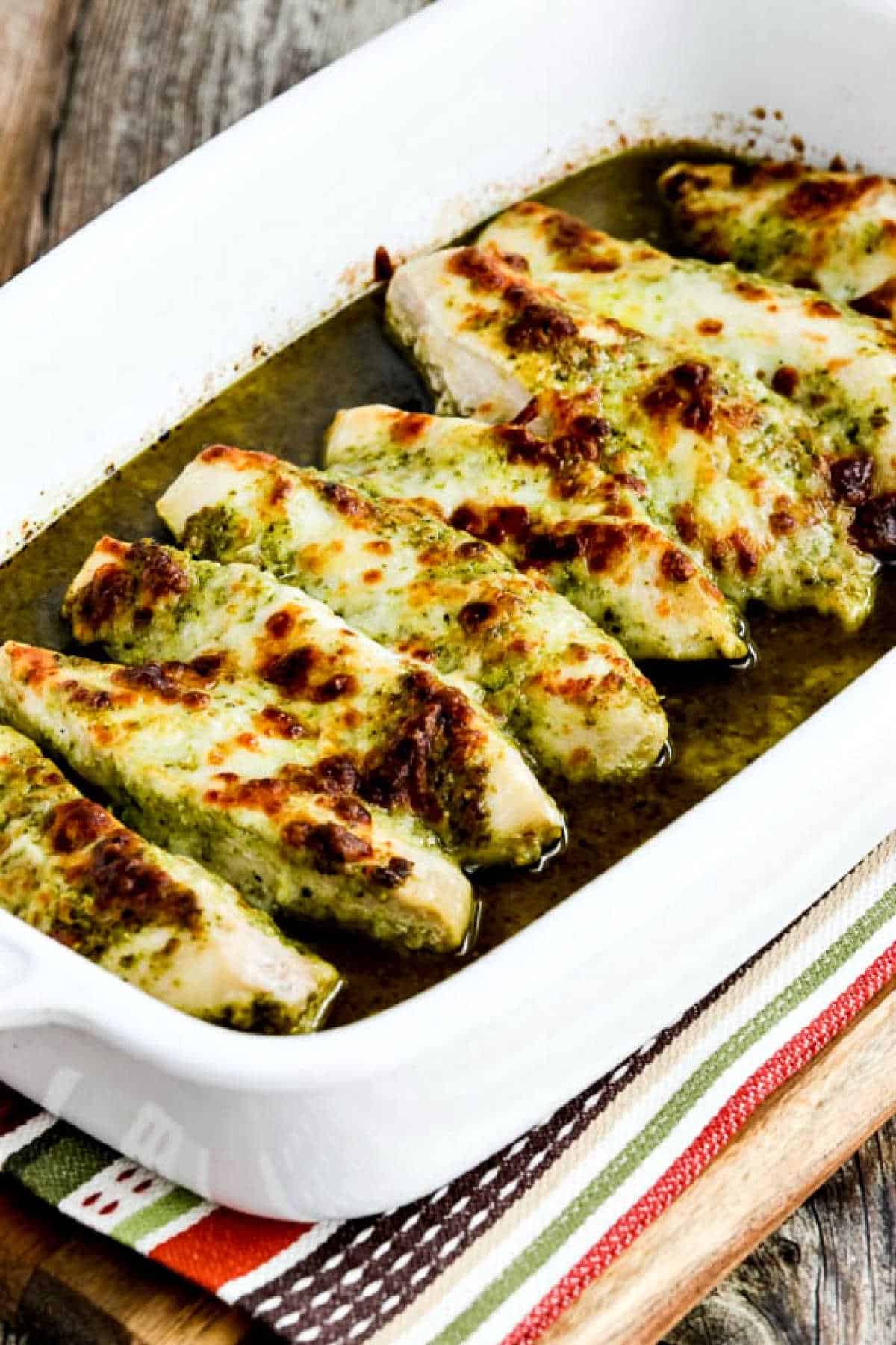 Easy Baked Pesto Chicken shown in baking dish with melted cheese