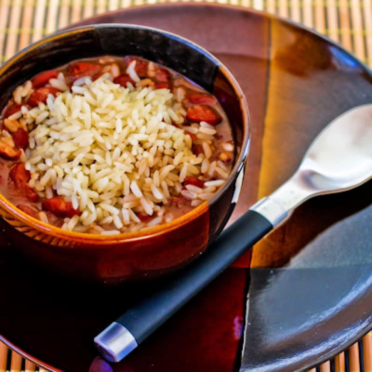 Square image for Slow Cooker Red Beans and Rice in serving bowl, on plate with spoon.