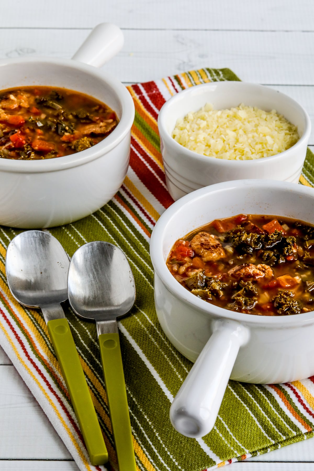 Slow Cooker Sausage Stew shown in two bowls with spoons and Parmesan.