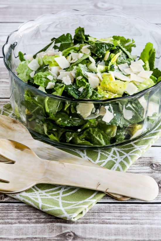 Caesar Salad with Kale, Romaine, and Shaved Parmesan shown in serving bowl with large serving forks