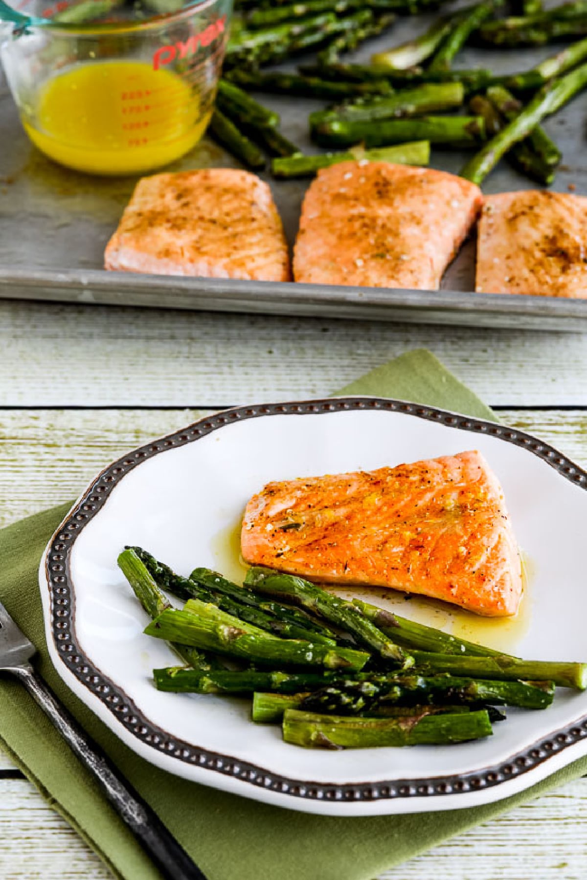 Salmon and Asparagus Sheet Pan Meal with one serving on plate and sheet pan in back.
