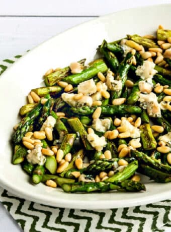 Square image of Pan-Fried Asparagus with Gorgonzola and Pine Nuts on serving plate