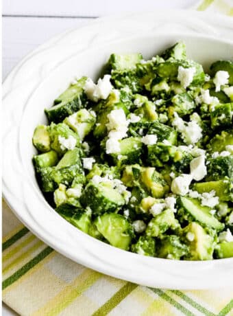 Cucumber Salad with Avocado and Feta shown in serving bowl on green-yellow napkin
