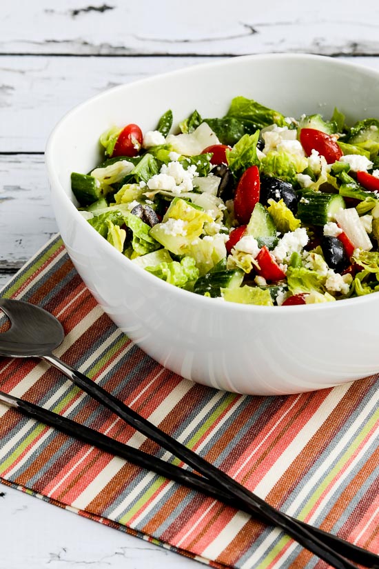 American greek salad on serving fork and serving bowl
