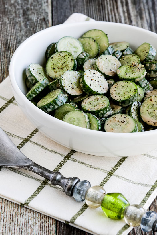 Cucumber salad with balsamic vinaigrette shown in a serving bowl with fork and napkin