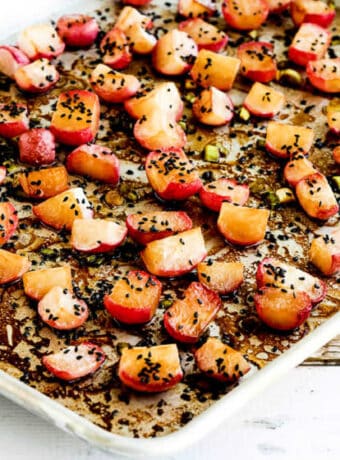 Square image of Roasted Radishes on baking sheet with sesame seeds sprinkled over.