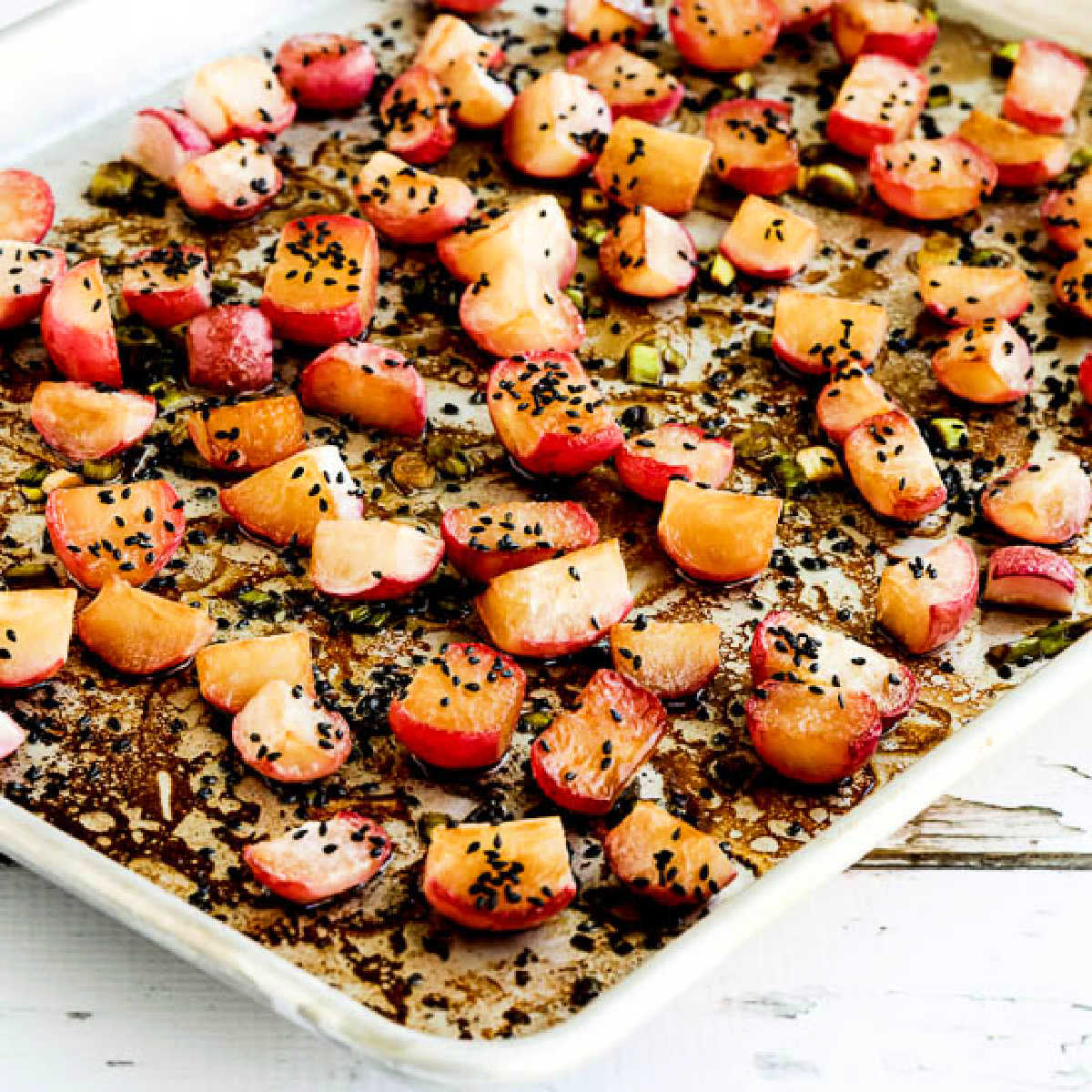 Square image of Roasted Radishes on baking sheet with sesame seeds sprinkled over.