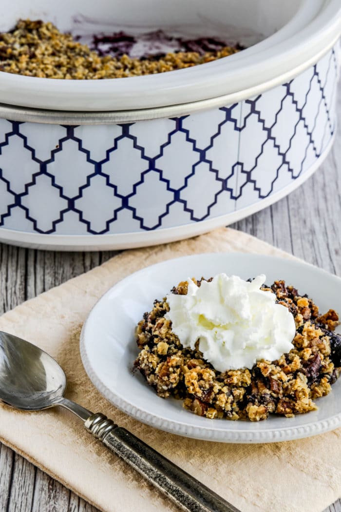 Slow Cooker Blueberry Crisp showing one serving and slow cooker in background