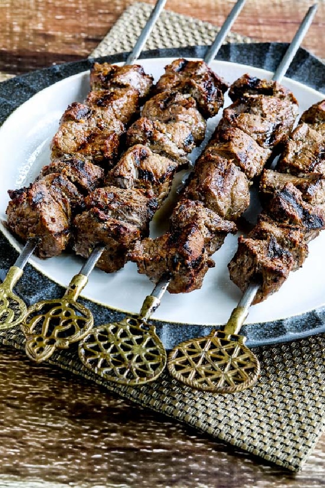 Low-Carb Marinated Beef Kabobs shown on serving plate with decorative skewers and napkin