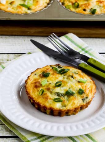 square image of Asparagus Breakfast Tarts with one on plate and tart pan in back