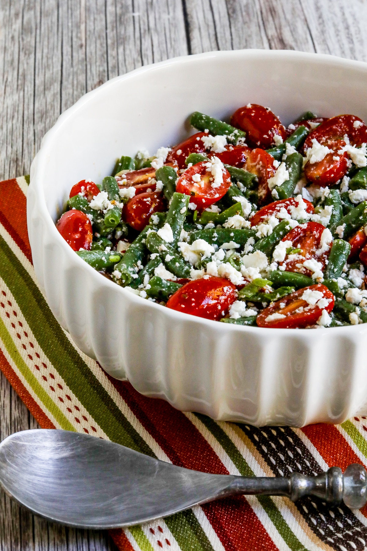 Green Bean Tomato Feta Salad in serving bowl with spoon.