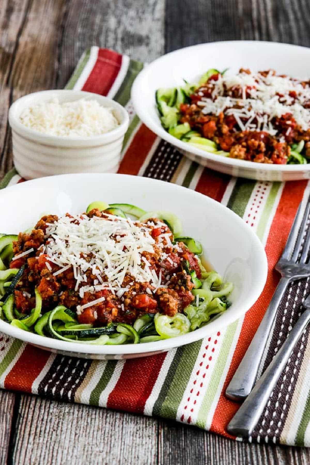 two serving bowls with zucchini noodles and Instant Pot Pasta Sauce on striped napkin
