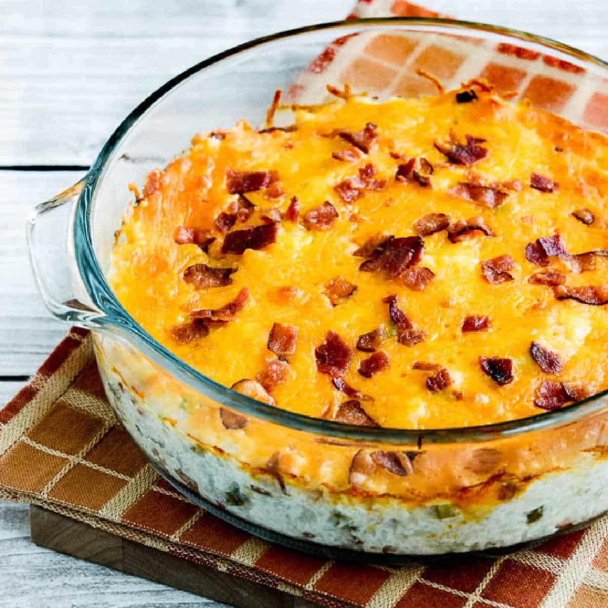 twice baked cauliflower in baking dish with melted cheese and bacon on top