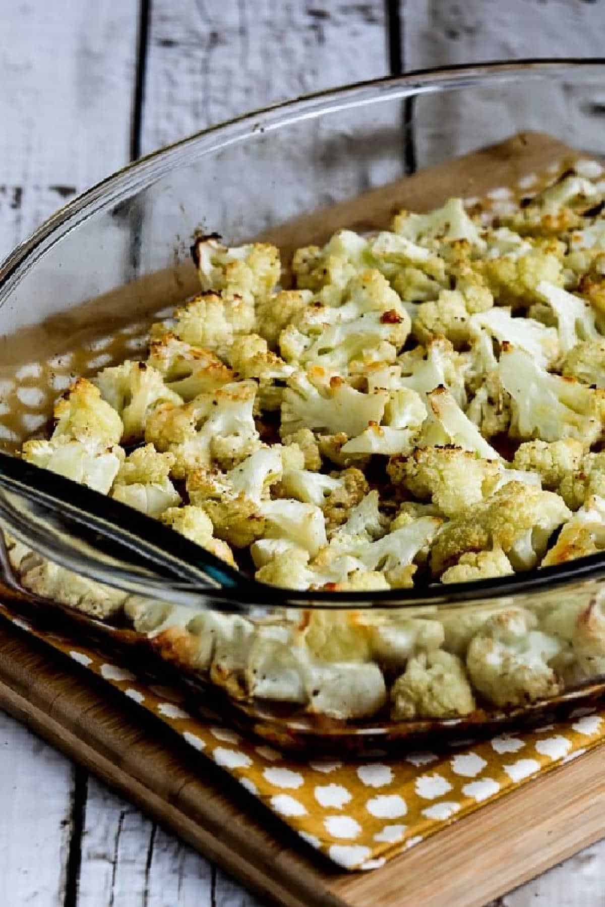 Roasted Cauliflower with Parmesan in baking dish on napkin and cutting board