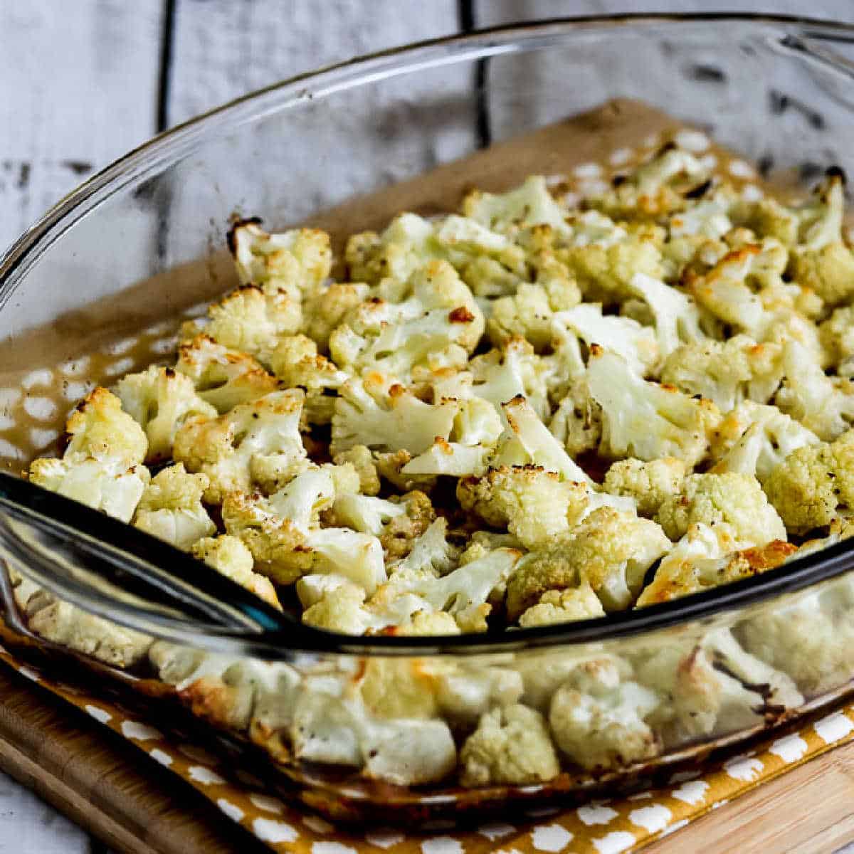 Square image of roasted cauliflower and parmesan cheese in a baking dish