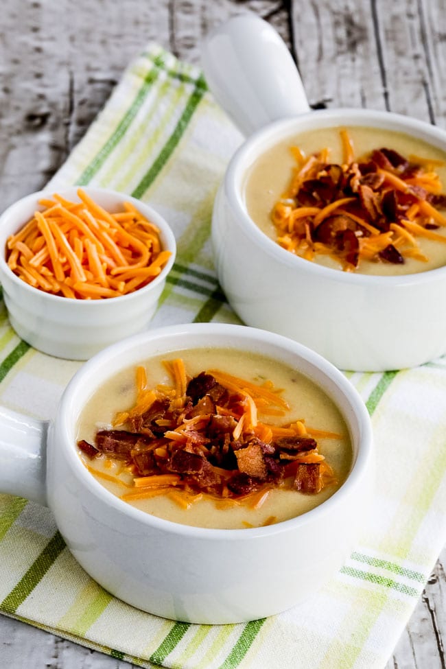 Cheesy Cauliflower Soup with Bacon and Green Chiles shown in two soup bowls on napkins.