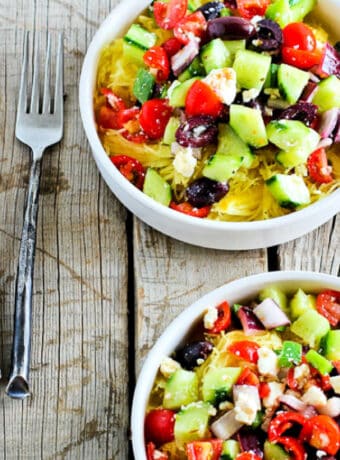 Square image for Greek Salad Spaghetti Squash Bowls with forks on wooden background.