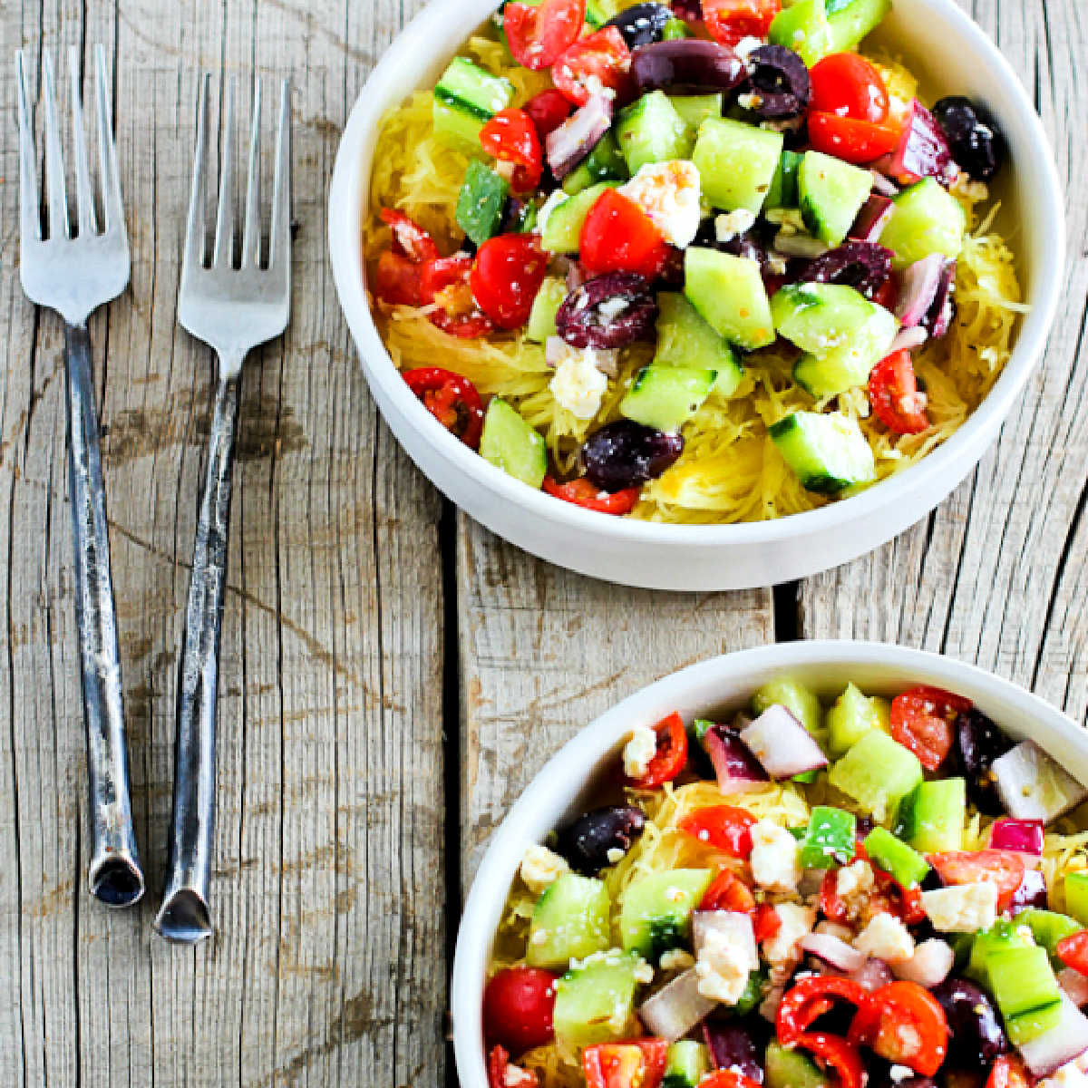Square image for Greek Salad Spaghetti Squash Bowls with forks on wooden background.