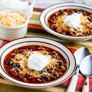 Instant Pot Ground Beef Olive Lover's Chili shown in two bowls with cheese and sour cream on the side