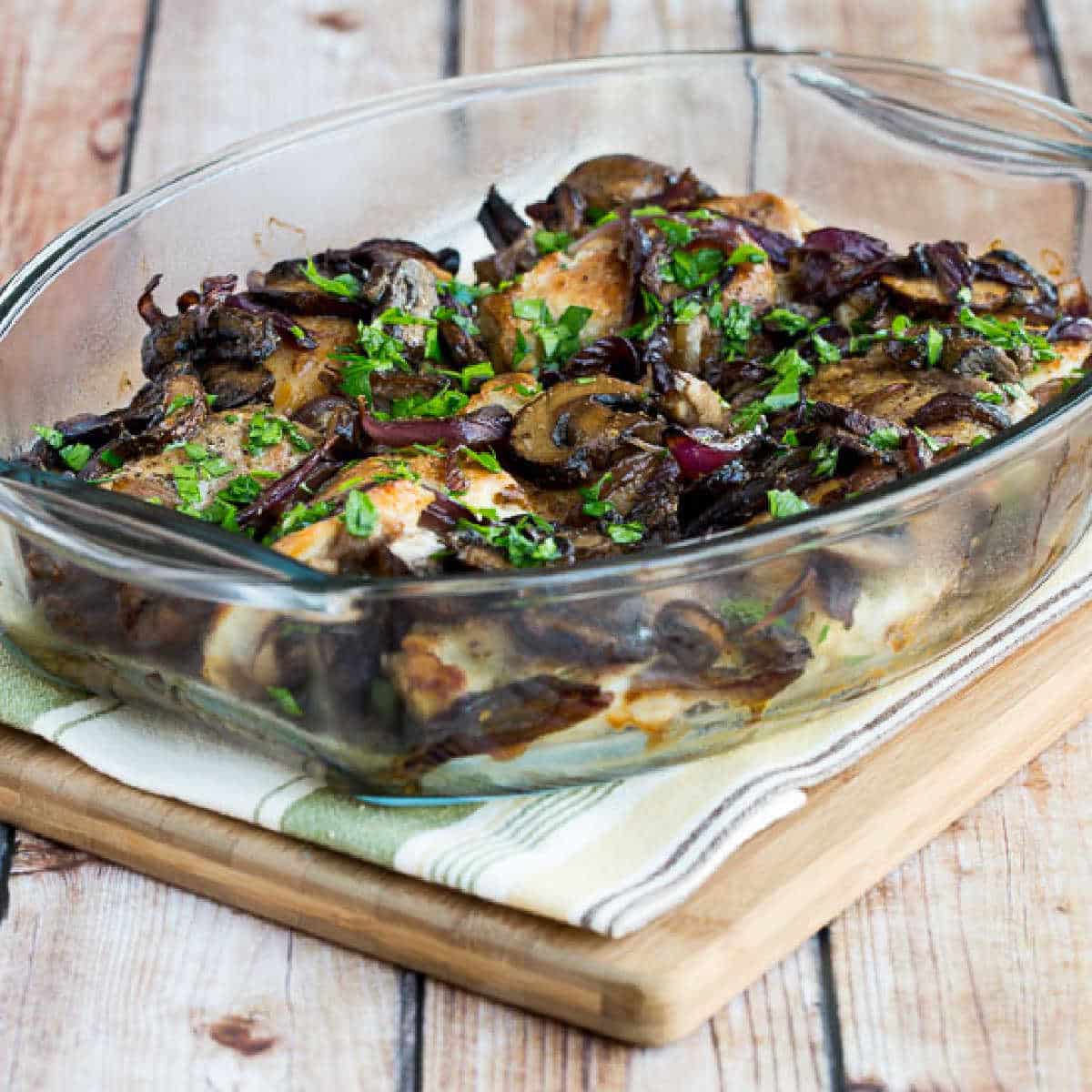 Chicken Thighs with Mushrooms shown on baking dish on napkin and cutting board
