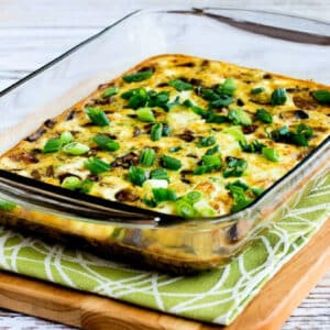 Square image for Sausage, Mushrooms, and Feta Baked with Eggs shown in baking dish on cutting board.