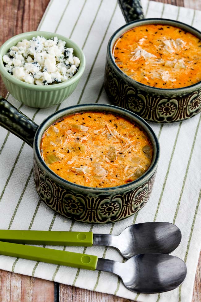 Instant Pot Buffalo Chicken Soup in two antique bowls with crumbled blue cheese on the side