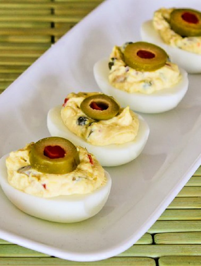 Deviled Eggs with Green Olives four eggs on serving plate with green olive slice