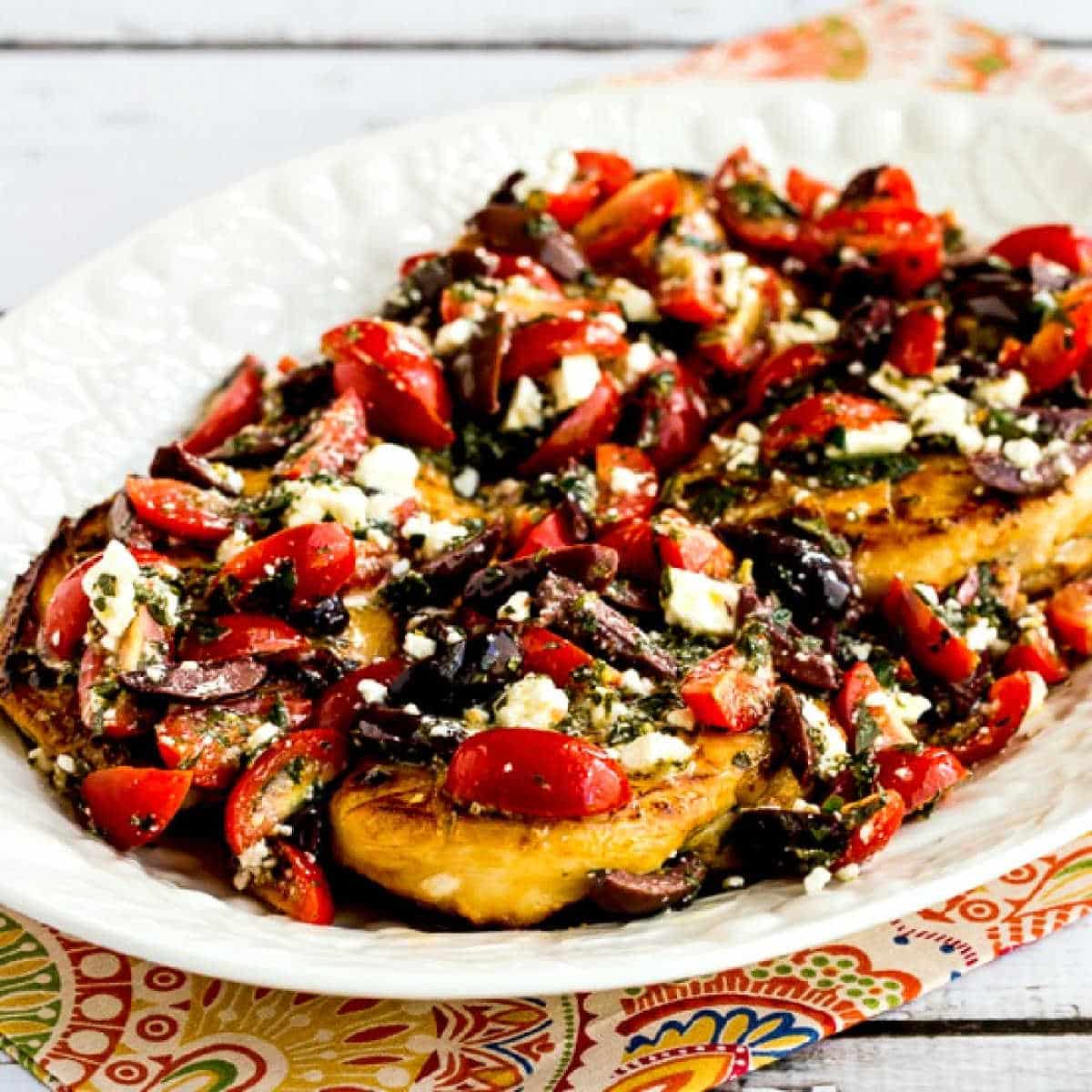 Greek Chicken with Tomato, Olive, and Feta Topping square image of chicken on serving platter
