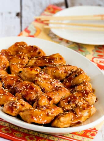 Square image of Spicy Asian Chicken on serving plate with chopsticks in background.